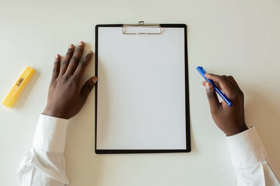 Mains posées de part et d’autre d’une fiche vierge sur un bureau clair