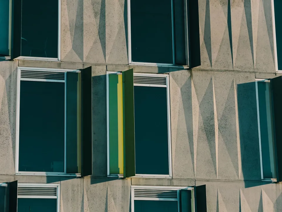 Façade en béton sculpté et volets verts, dans la lumière de fin de journée