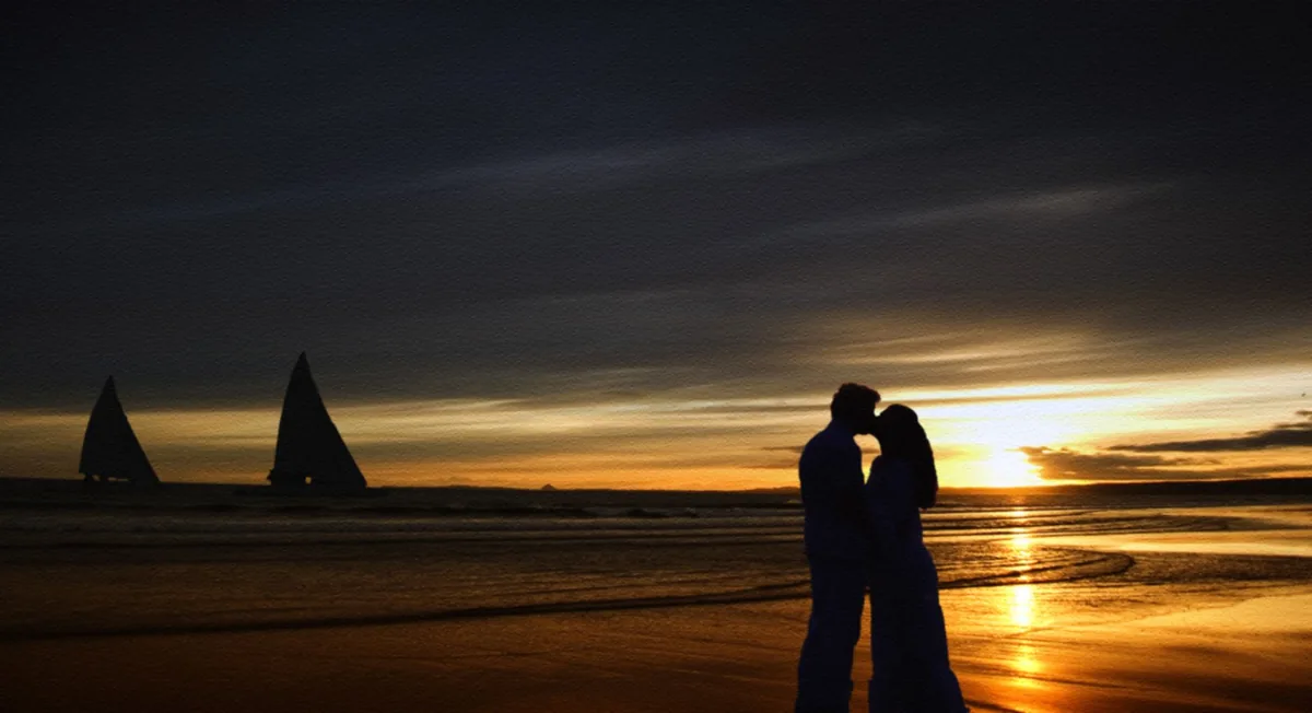 Un couple marchant sur une plage au coucher du soleil.
