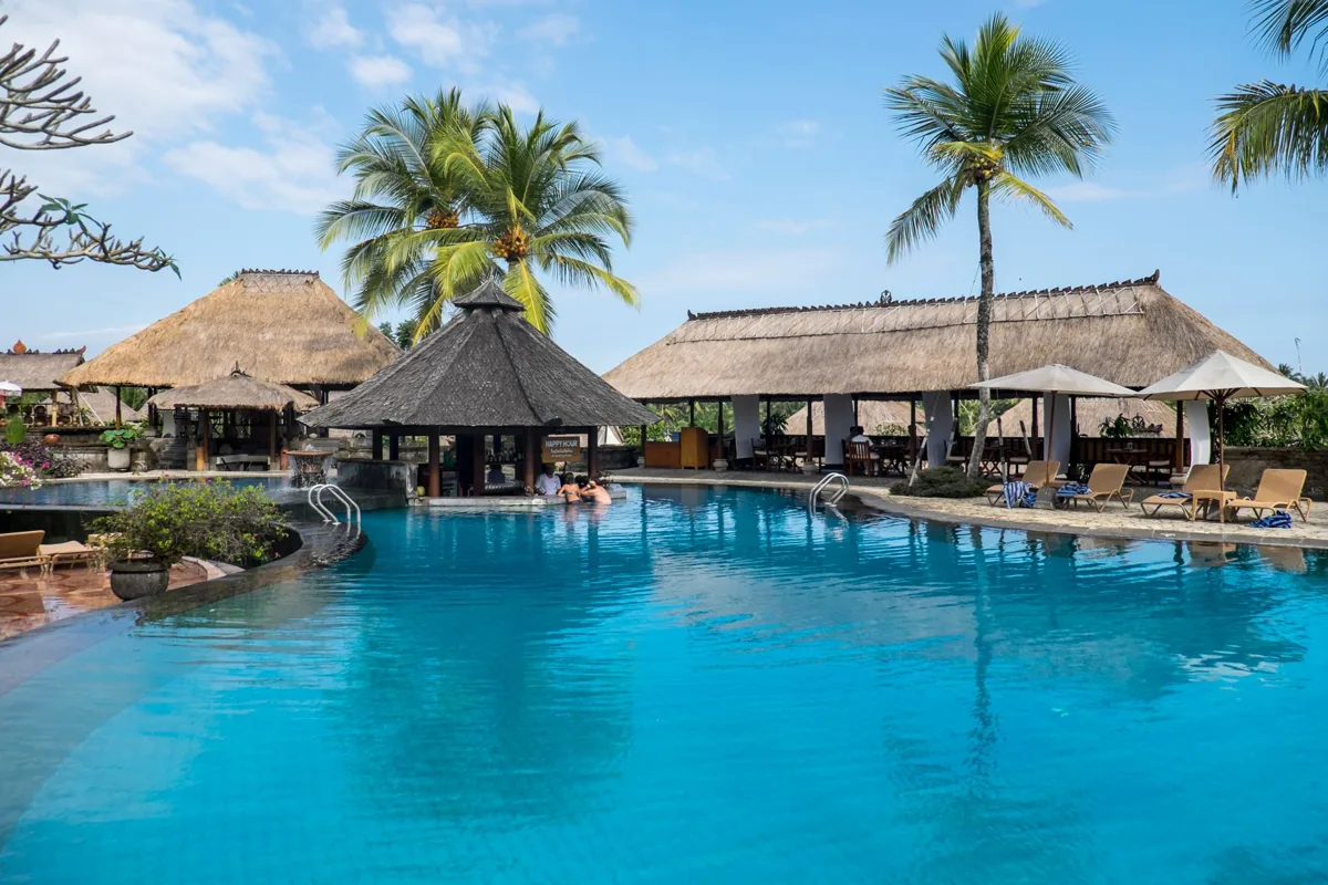 La piscine d’un hôtel de standing, transats au bord.