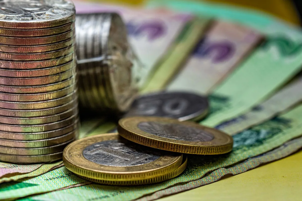 Des pièces et billets en francs CFA — un paysage sénégalais.